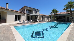 A swimming pool with geometric patterns, a two-story building with balconies, and lounge chairs. - Pool, 4 chambres, 4 SdB, clima, cuisine extérieure, grands jardins, aire de jeux (Carpentras)