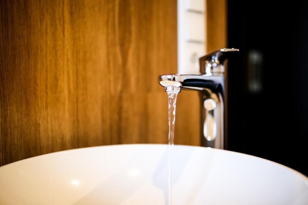 Ein weißes Waschbecken, aus dem Wasser aus einem modernen Wasserhahn fließt.