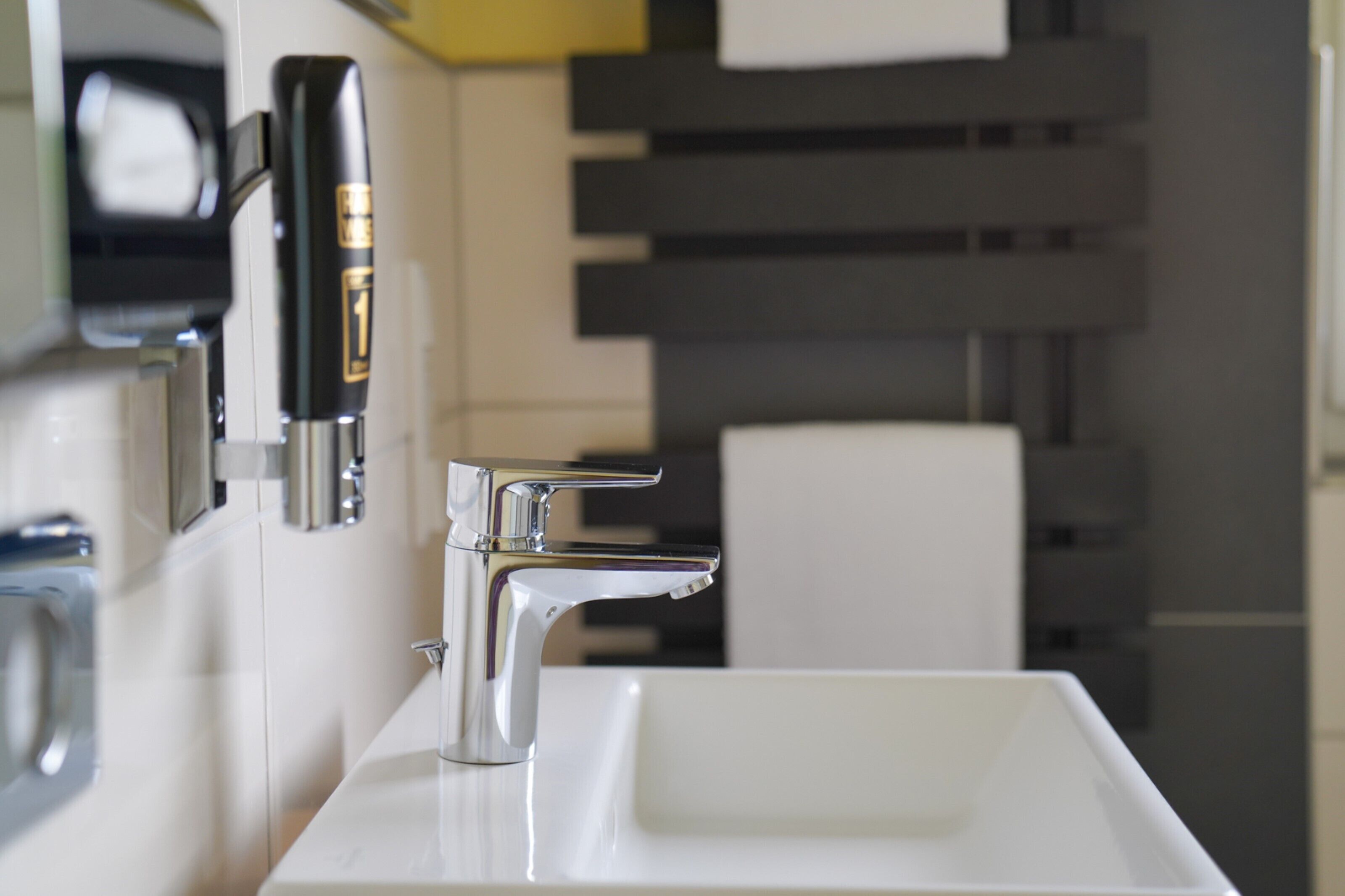 A modern bathroom with a chrome faucet, a white sink, and a towel rack.