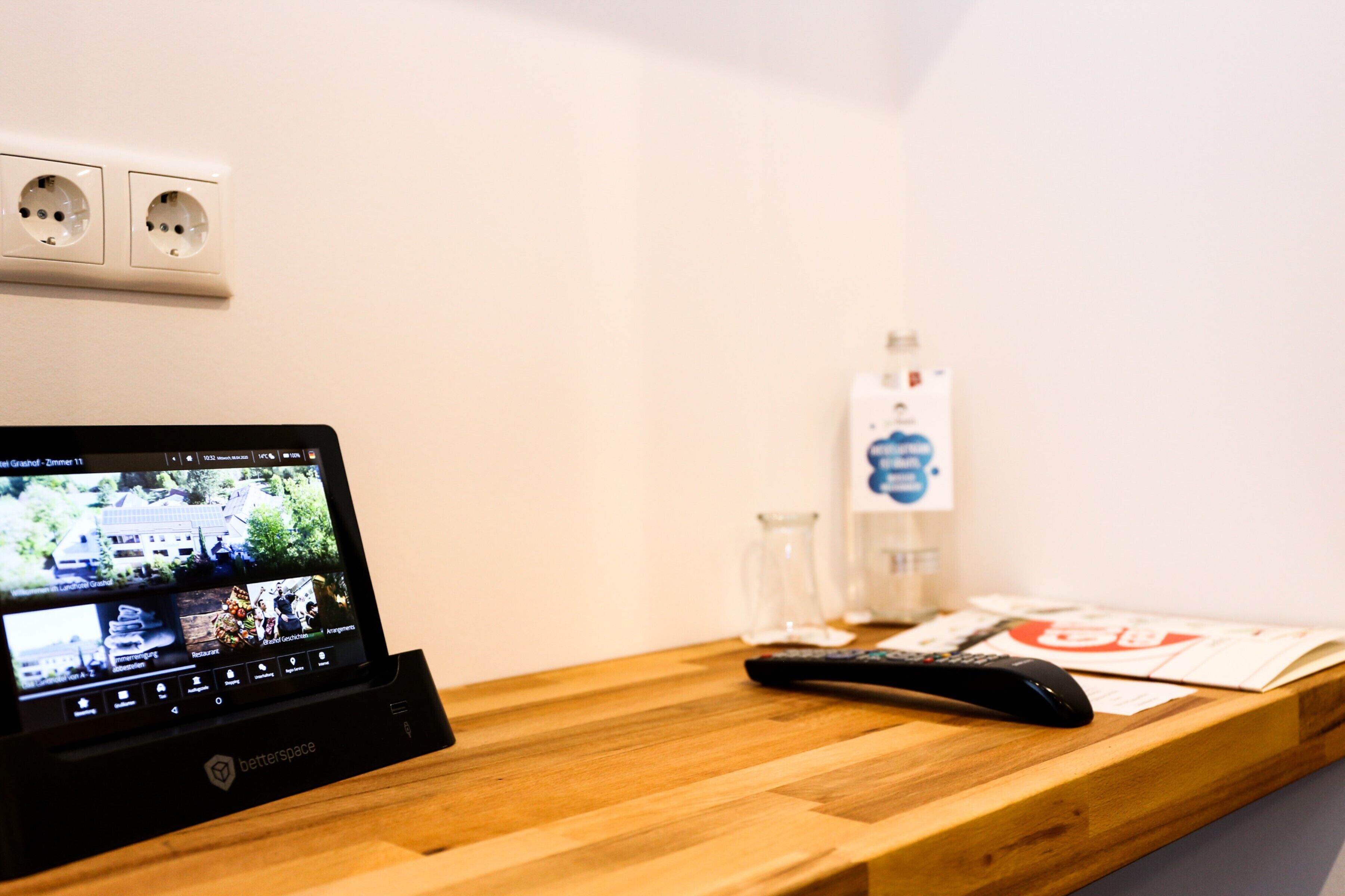 A Betterspace device on a wooden table with a remote control and papers.