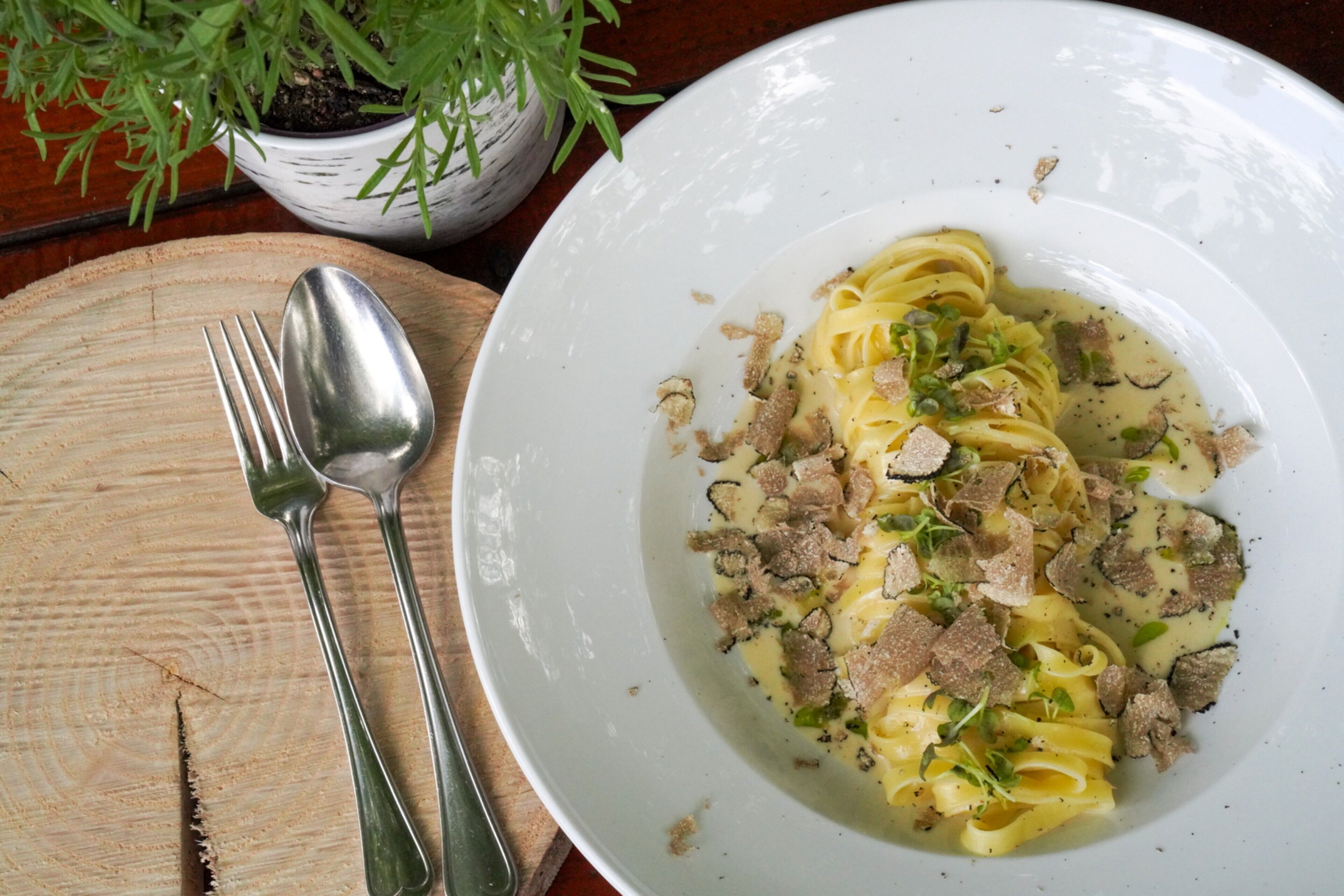 Ein Teller Pasta mit Fleisch und Käse auf einem Holztisch.