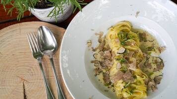 Ein Teller Pasta mit Fleisch und Käse auf einem Holztisch.