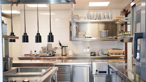 A modern kitchen with stainless steel appliances, a coffee machine, and hanging lights. - Landhotel Grashof (Kalbach)