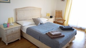 Una camera da letto ordinata con un letto, comodini, una sedia e una finestra con tende.