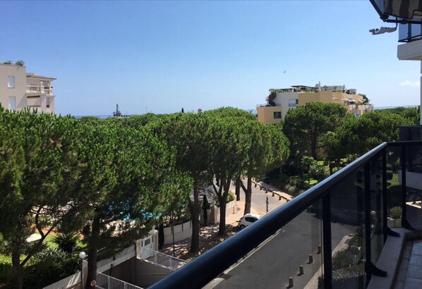 A residential area with modern buildings, a clear sky, and a view of the sea.