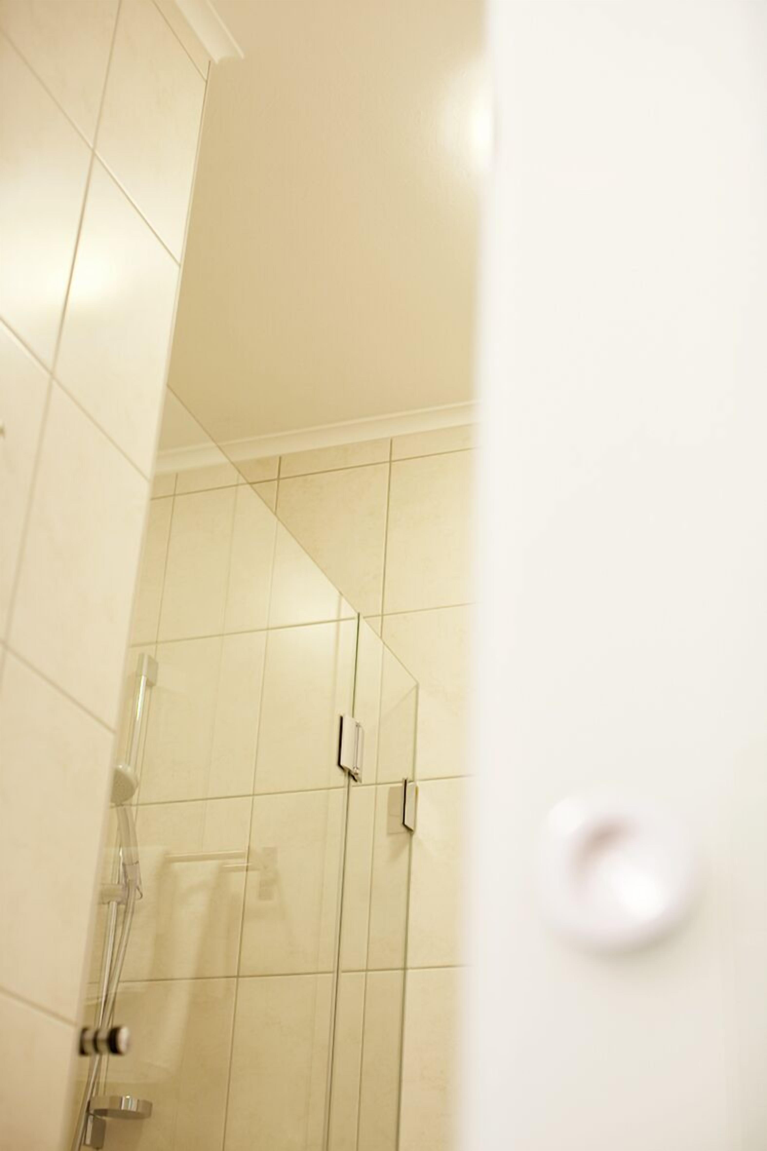 Une salle de bain avec des murs recouverts de carreaux blancs et un espace douche.