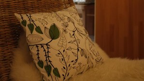 A cozy room with a wicker sofa, a fluffy white rug, and a wooden side table. - Flörsbacher Hof (Floersbachtal)