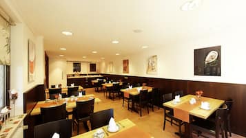 A restaurant with multiple tables and chairs, wooden paneling on the walls, and ceiling lights.