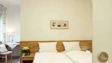 Un dormitorio con una cama de madera, una mesita de noche con lámpara, un tapete verde y un cuadro enmarcado en la pared.