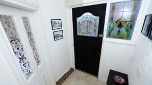 A hallway with a black door, patterned wallpaper, and a small table with a decorative item.