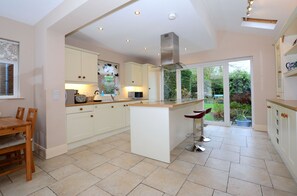 A spacious kitchen with a central island, white cabinetry, and a large window providing a view of the garden. - Lovely house with a mature garden and is fully serviced and a home from home (Belfast)
