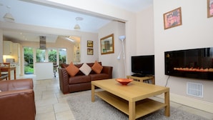 A modern living room with a brown leather sofa, a wooden coffee table, and a flat-screen TV mounted on the wall.