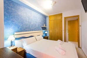 A bedroom with a bed, bedside table, lamp, and wooden wardrobe.