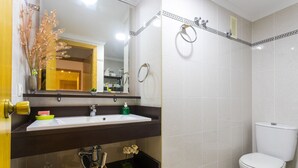 A bathroom with a white sink, mirror, and toilet. There are shelves with toiletries and a decorative plant. - ApartUP Saplaya Harbour (Alboraya)