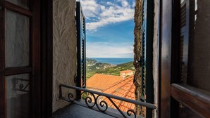 Una ventana con vistas a edificios de tejas color terracota y un cielo despejado.