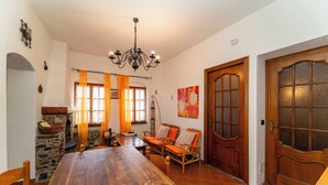Un comedor con una mesa de madera, sillas de mimbre y una pared de piedra.