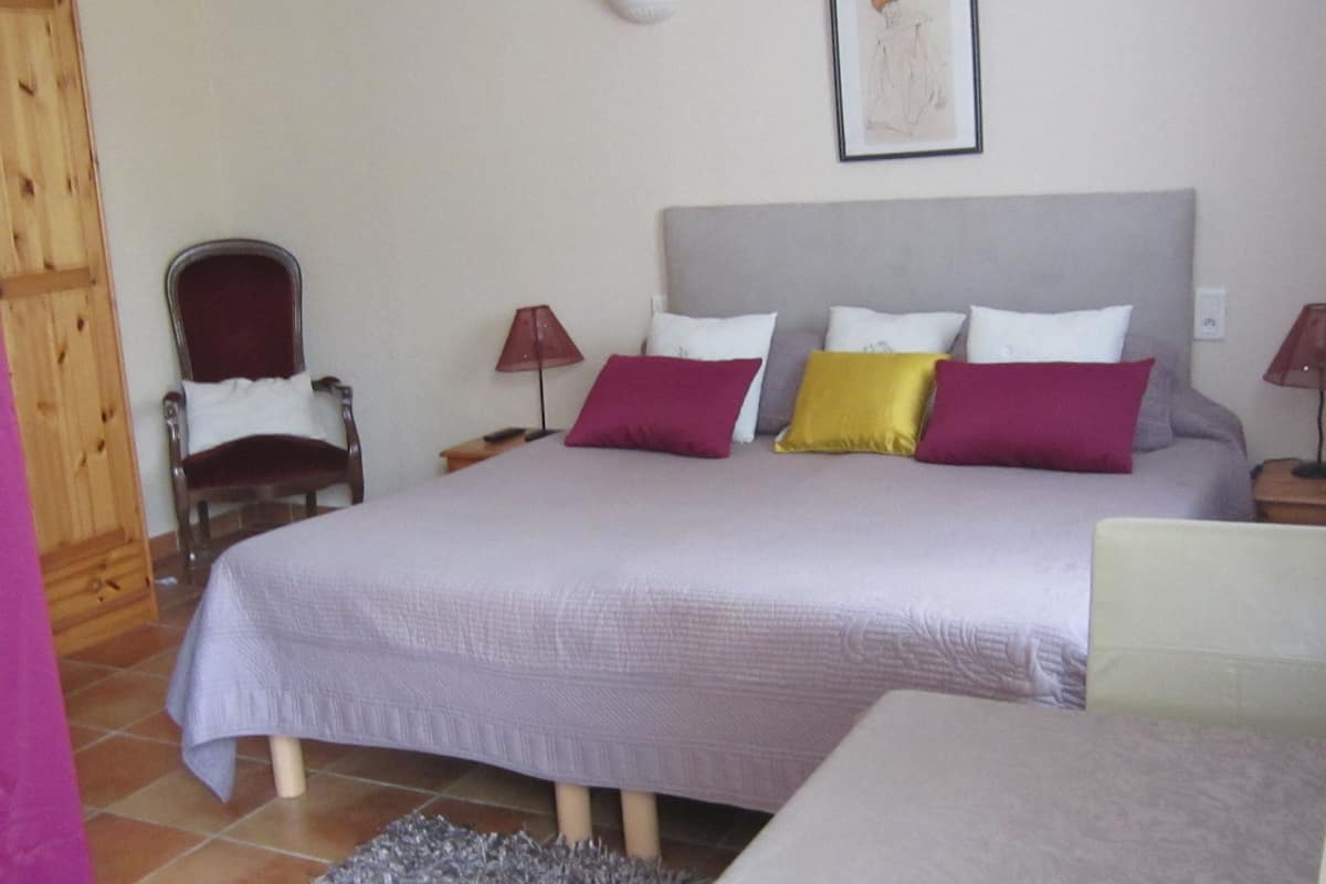 A bedroom with a bed, two nightstands, a chair, and a lamp.