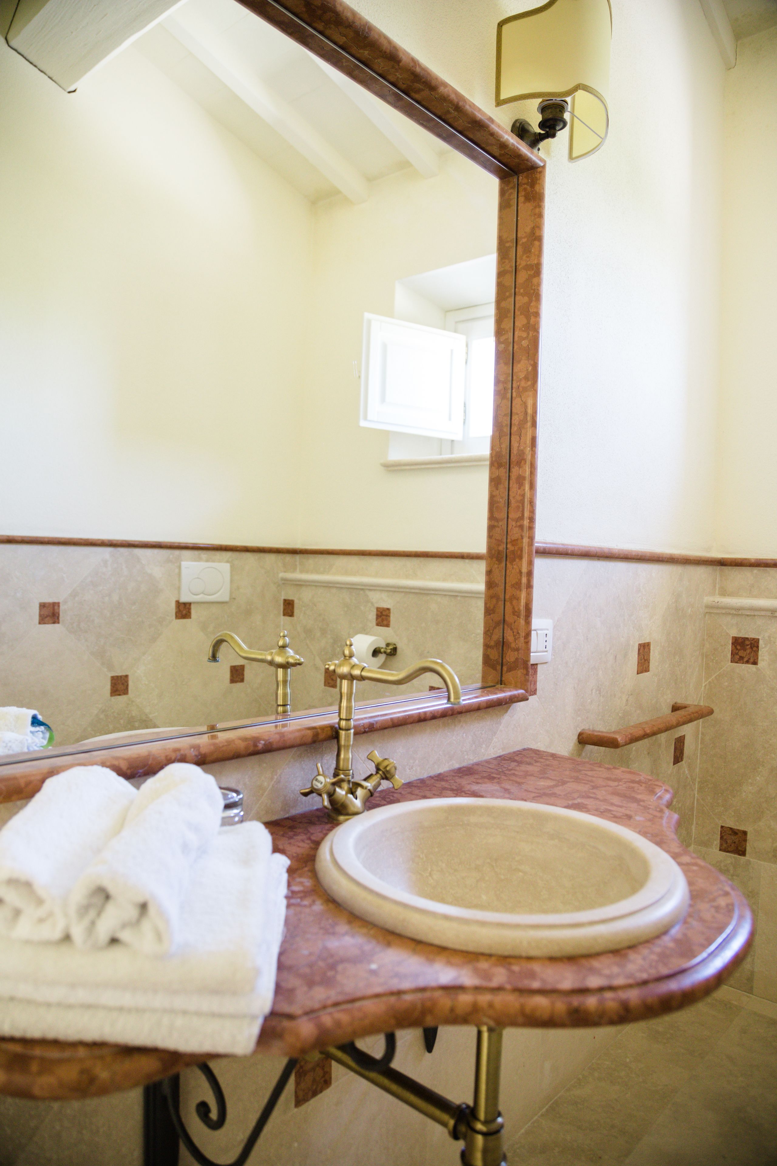 A bathroom with a marble sink, a mirror, and a towel rack.