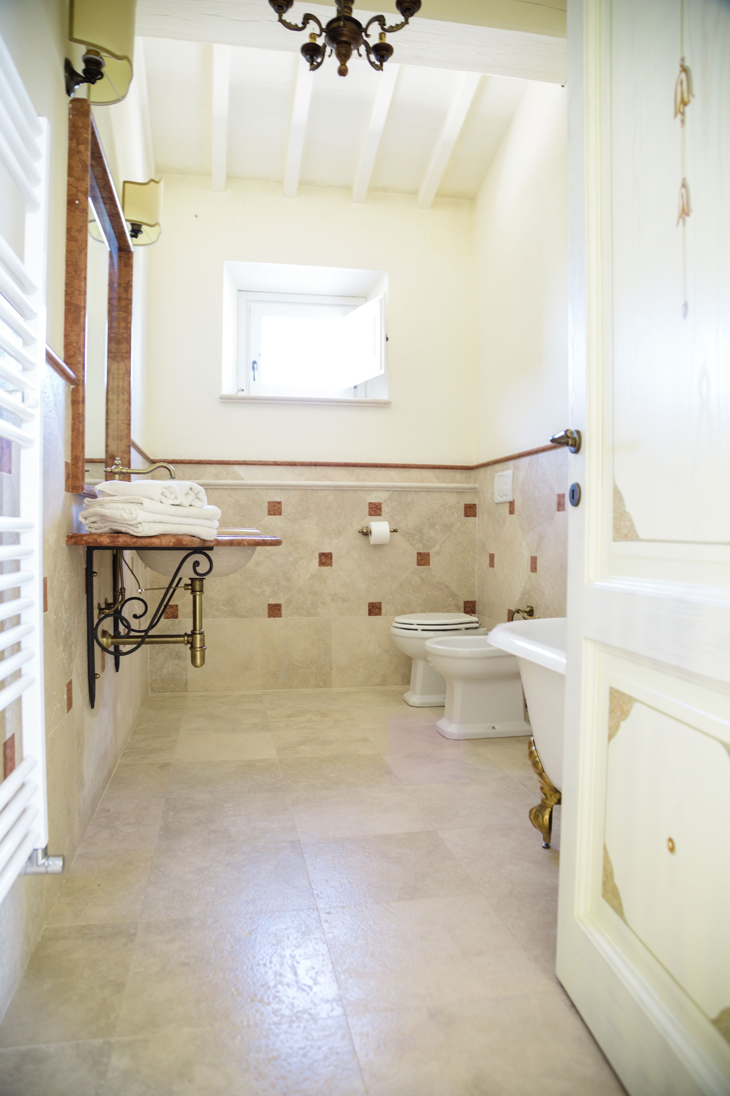 Ein schmales Badezimmer mit Toilette, Waschbecken und einem kleinen Fenster.