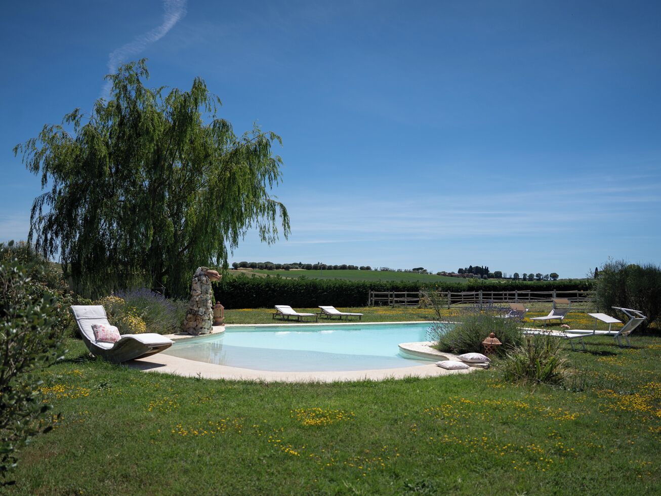 Une piscine ronde entourée de chaises longues, avec un arbre au centre.