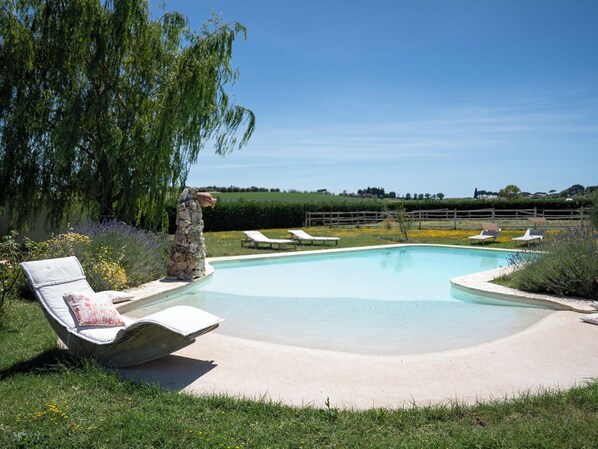 Une piscine dotée de chaises longues et d’une structure en pierre.