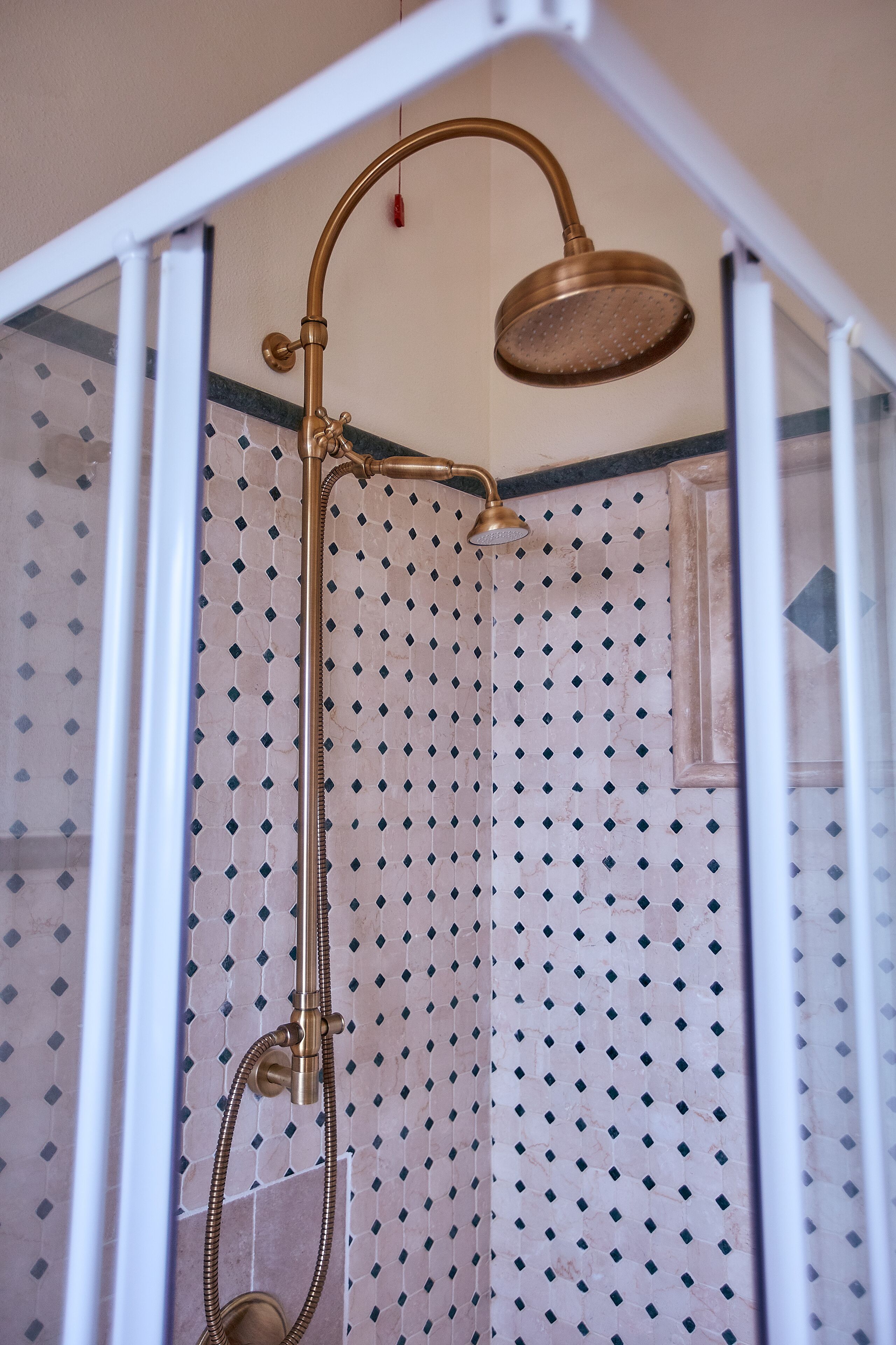 A shower with a curved showerhead and a handheld showerhead.