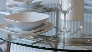 A dining table with a white vase containing flowers, clear glassware, and stacked plates. - The Huntington - Donnini Apartments (Ayr)