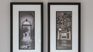 Two framed black and white photographs of urban scenes, one depicting a street with an archway and the other showing a street with buildings and a lamppost. - The Huntington - Donnini Apartments (Ayr)