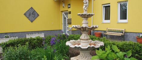 A yellow building with a fountain, a bench, and a sign marked "HOTEL".