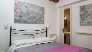 A bedroom with a bed, a nightstand, and two wall-mounted lamps. - PalermiT'Amo Apartment (Palermo)