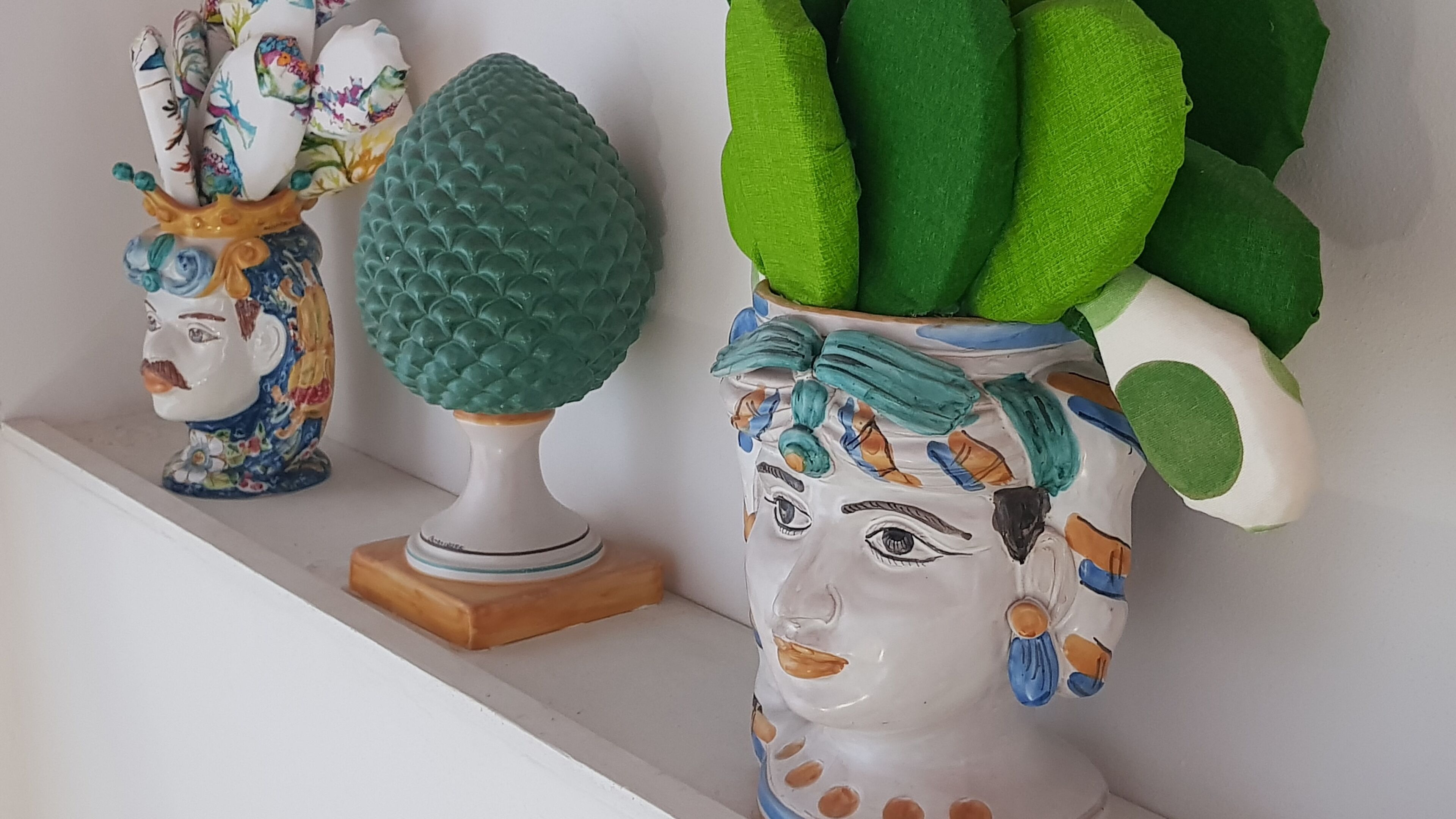 Trois vases en céramique, de différentes formes et textures, sont disposés sur une étagère.