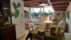 A cozy kitchen with a dining area, wooden ceiling, and large windows overlooking a garden. - PalermiT'Amo Apartment (Palermo)