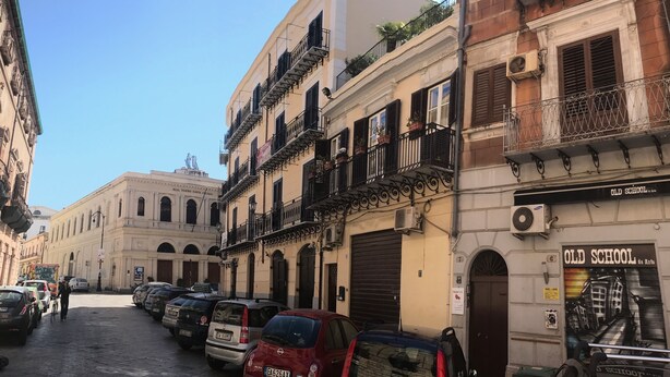 A street with parked cars and buildings, including a theater and an old school. - PalermiT'Amo Apartment (Palermo)