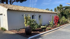 A building with a tiled roof, a small door, and a garden with various cacti and plants. - Guesthouse Le Mas de la Dame (Saint-Tropez)