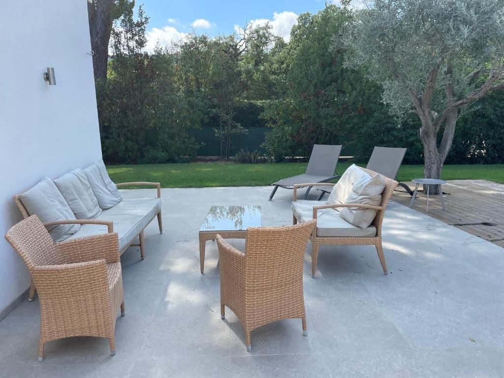 An outdoor seating area with wicker furniture and a glass table.