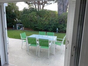 An outdoor patio with a table and chairs, a grill, and a hedge in the background. - Guesthouse Le Mas de la Dame (Saint-Tropez)