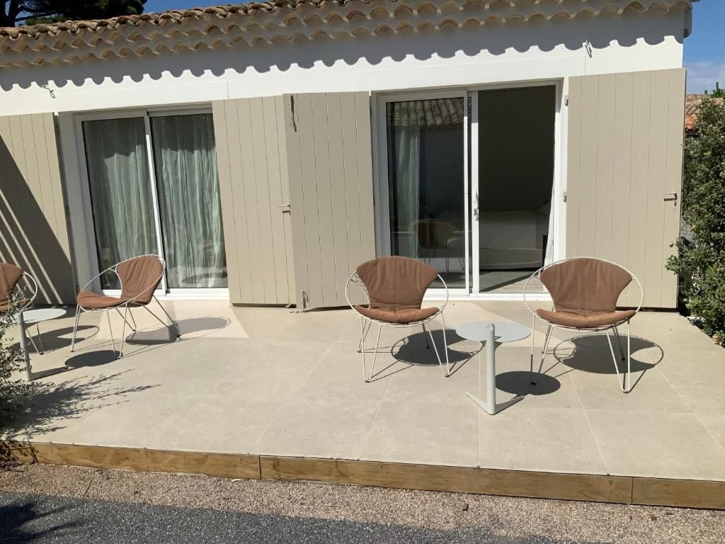 A building with a patio area featuring two chairs and a small table.