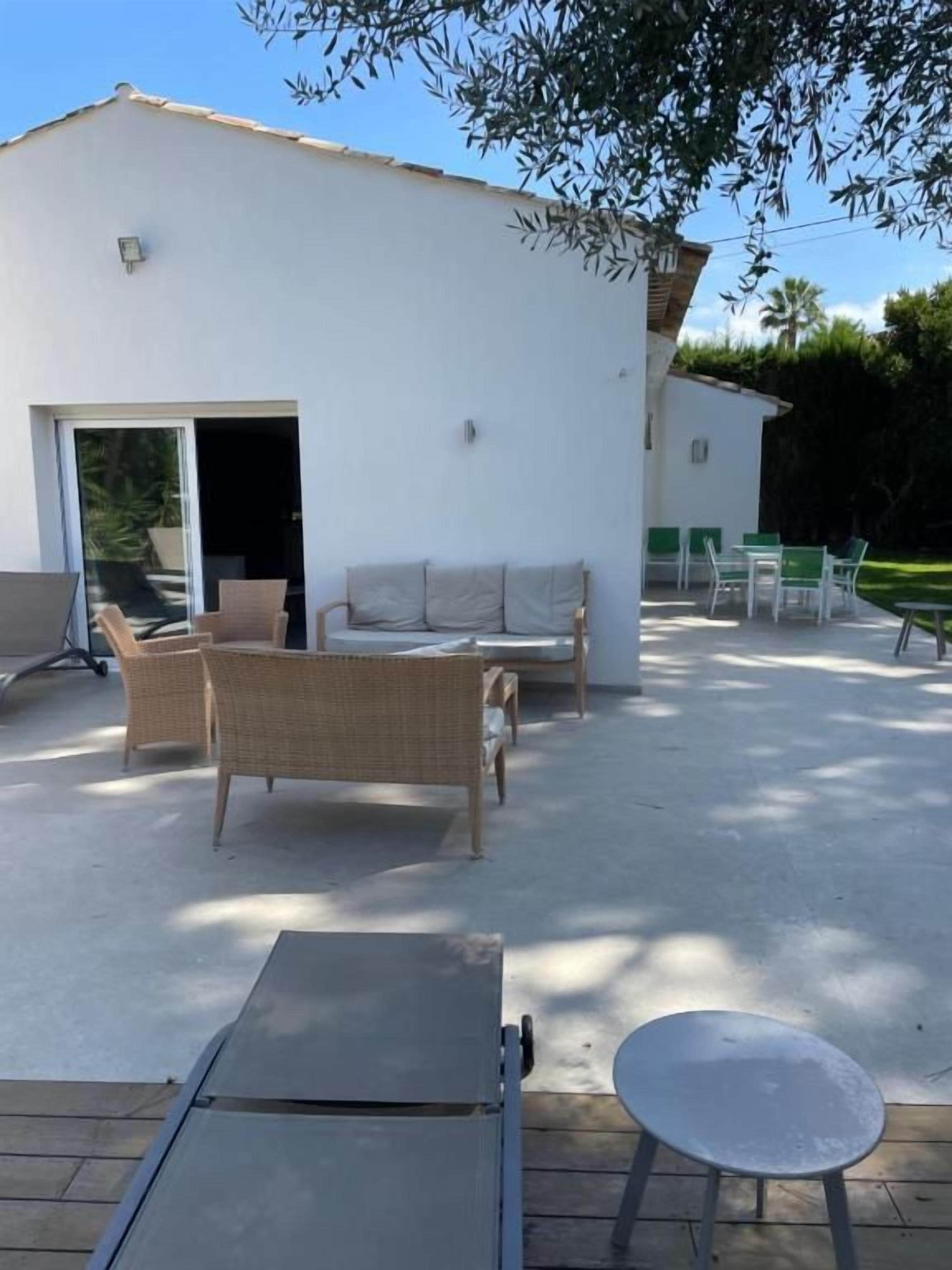An outdoor patio area with a white building, wicker furniture, and a table.