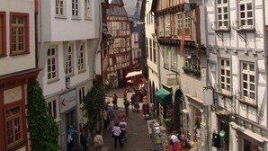 Eine schmale Kopfsteinpflasterstraße, gesäumt von traditionellen Fachwerkhäusern, von denen einige mit Geschäften und Schildern versehen sind.