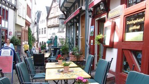 Eine schmale Straße mit Außenbestuhlung eines Restaurants, inklusive Tischen und Stühlen.