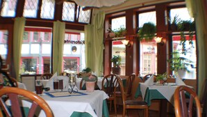 Ein Restaurantinneres mit gedeckten Tischen, Stühlen und Zimmerpflanzen.