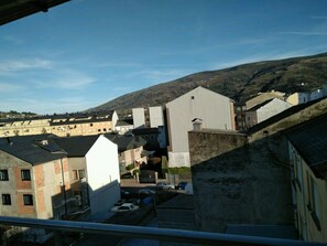 A residential area with buildings, a parking lot, and a hill in the background. - Hostal Mayo (O Barco de Valdeorras)
