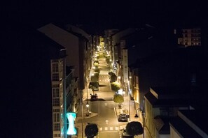 A nighttime street view with buildings on either side, streetlights, and a clear road. - Hostal Mayo (O Barco de Valdeorras)