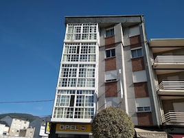 Un edificio de varios pisos con un llamativo letrero de Opel, que indica un espacio comercial en la planta baja.
