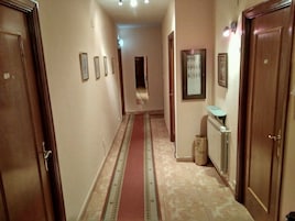 Un pasillo con puertas de madera, un radiador y suelo de baldosas.