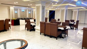 A modern restaurant with marble flooring, brown upholstered chairs, and a glass-top table. - Hotel Akbar International (Rawalpindi)