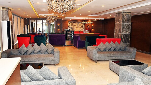 A modern lobby with grey sofas, a chandelier, and a reception desk. - Hotel Akbar International (Rawalpindi)