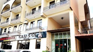 A multi-story building with a restaurant named "Chai & Co" on the ground floor. There are steps leading to the entrance, and a white car is parked in front. - Hotel Akbar International (Rawalpindi)