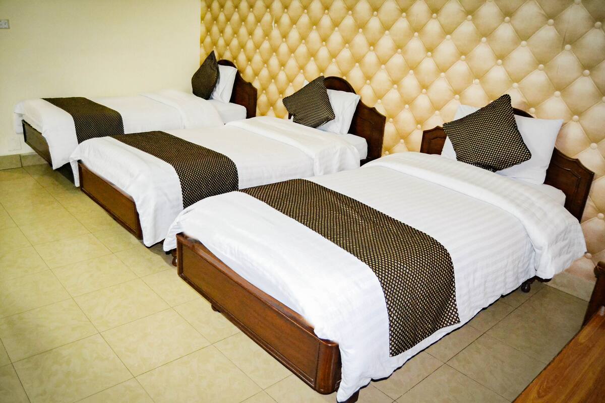A hotel room with two double beds, a tufted headboard, and a tiled floor.