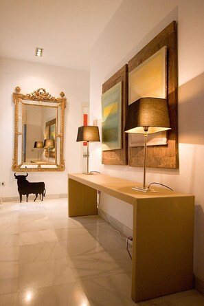 A modern interior with a large mirror, two wall-mounted lamps, and a desk.
